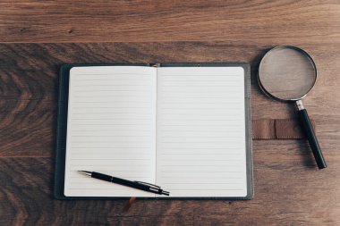 Tahta bir masanın üzerinde büyüteçle birlikte not defterini aç