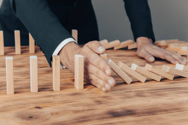 Risk and Strategy in Business, Image of hand stopping falling collapse wooden block dominoes effect from continuous toppled bloc