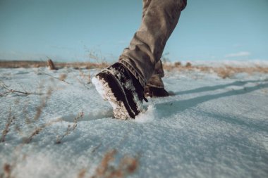 Bir adam açık havada karda yürür.