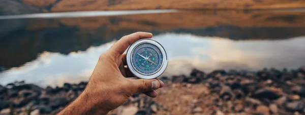 stock image Man holding a compass by the lak