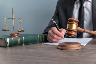 Yargıç kağıtları imzalar ve tokmakla vurur. Adaletin terazisi