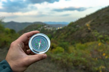 Ormanların ve dağların arka planına karşı bir pusula tutuyor