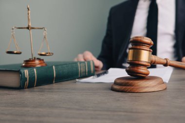 Yargıç masanın önünde oturuyordu. Çekiç ve teraziler masanın üzerinde.