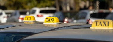 Several cars with a taxi sign stand at nigh