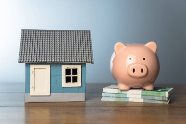 House, piggy bank and banknotes on the tabl