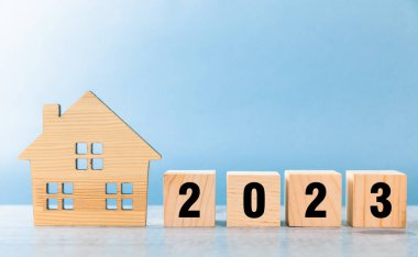 Evin şekli ve masadaki küplerin üzerindeki 2023 yazıları.