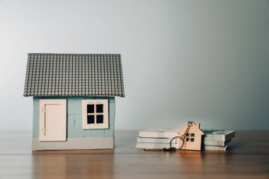 Dolar banknotları ve masada anahtarları olan bir ev.