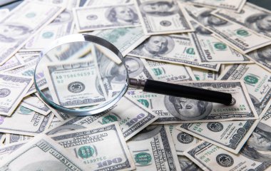 Dolar banknotları ve masanın üzerinde büyüteç.