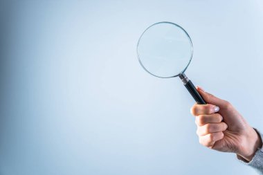 Gri sırtüstü büyüteç tutan genç kadın.