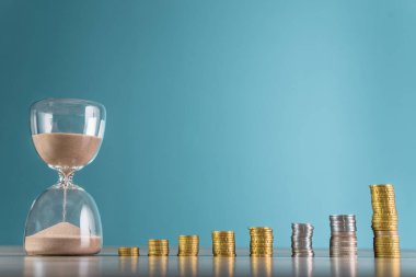 Bozuk paralar ve kum saatleri ahşap masada.