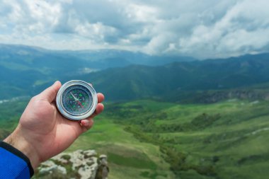 Bir dağın arka planına karşı bir pusula tutar