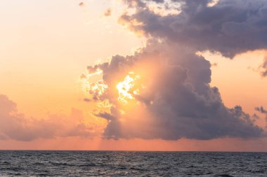 Kızıl güneş denizin üzerindeki bulutların arkasında. Kırmızı güneş