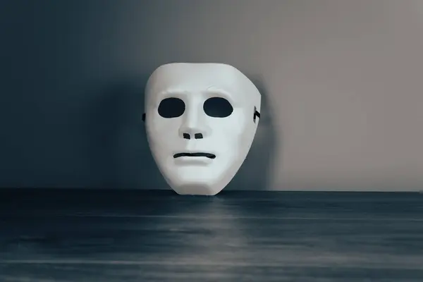 White anonymous mask on a wooden tabl