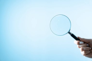 Gri bir sırtüstü büyüteç tutarken
