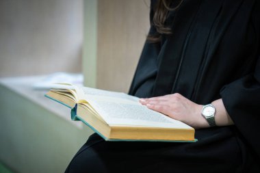 Bayan öğrenci içeride kitap okuyor.