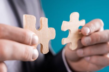 Takım elbiseli adam yapboz parçasını tutuyor.