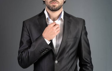 Takım elbiseli bir adam yakasını kanepede düzeltir.