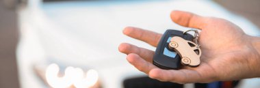 Arabanın arka tarafındaki adam arabanın anahtarını tutuyor.