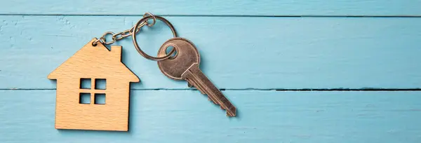 Symbol of the house with silver key on wooden backgroun