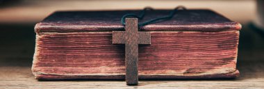 Masanın üzerinde tahta haç olan kutsal İncil.