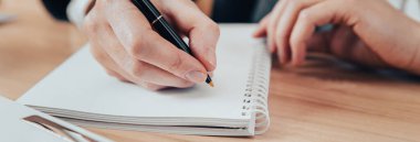 Adam elinde kalem tutarak kağıt okuyor ve çalışmalarını yansıtıyor.