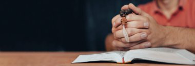 Kutsal Bibl ile haç tutan dua eden adam.