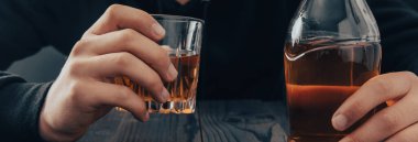 Yakından bir şişe viski ve bardak tutan iş adamları.