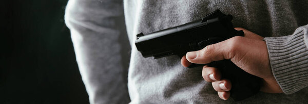 Человек с пистолетом в спине на темном заднем плане