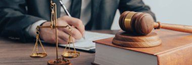 Yargıcın tokmağının masada olduğu adalet terazisi. Bir adam bir blo üzerine yazar