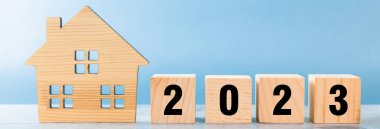 Evin şekli ve masadaki küplerin üzerindeki 2023 yazıları.