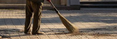 Janitor sweeping dirt on the street during the da