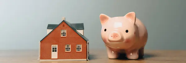 Piggy bank and a house on a wooden tabl