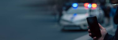 Şehirde polis arabalarının arka planına karşı telefon tutmak...