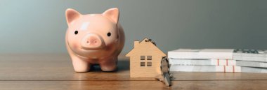 Domuz kumbarası, ev anahtarları ve masanın üzerindeki para.