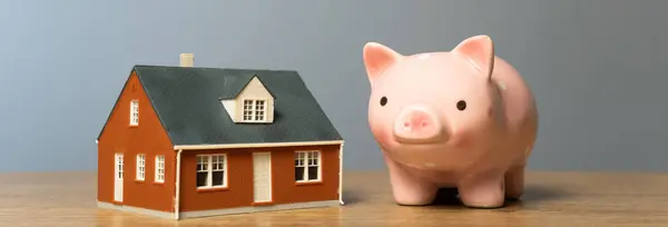 Piggy bank and a house on a wooden tabl