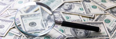 Dolar banknotları ve masanın üzerinde büyüteç.