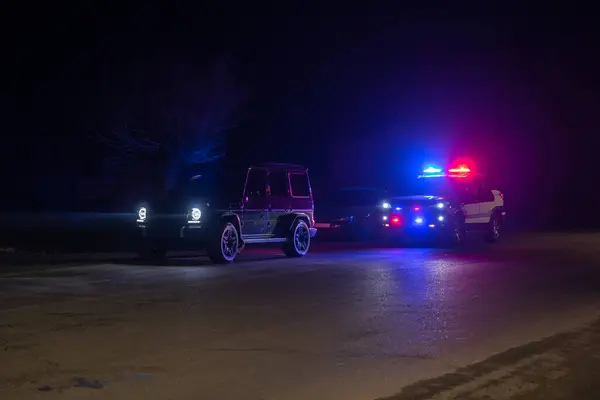 Polis arabası hız yaptığı için kenara çektiği bir arabanın yanında duruyor ve sürücünün kimliğine ulaşıyor. , stok fotoğrafı