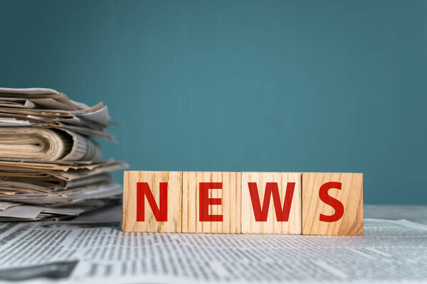 Газеты и деревянные кубики со словом "новости" на синем фоне фото