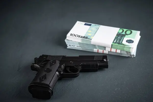 Gun and money on black background, stock photo, criminal concept
