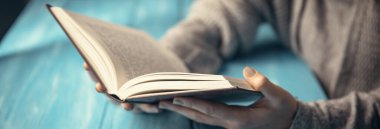 Mavi masa sırtüstü kitap okuyan kadın