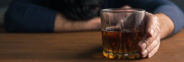 Üzgün adam masanın üstünde alkol bardağı var.