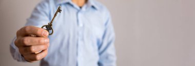 Gray Backgroun 'da adamın elinde klasik anahtar var.