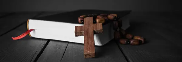 wooden cross on book on the dark des