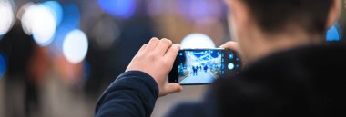 Adam elinde akıllı telefon fotoğrafı var.