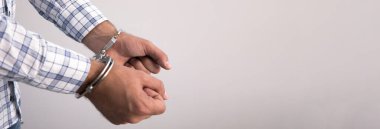 Gri sırtüstü kelepçelenmiş genç adam.