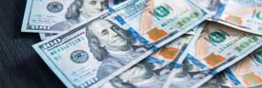 Siyah ahşap masaya yığınla yüz dolar.