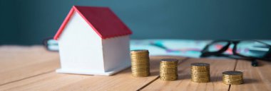 Bozuk paralar ve ev modelleri masa arkasında.