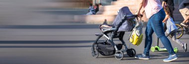 Bebek arabalı bir kadın sokakta yürüyor.