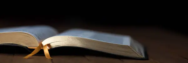 İncil, karanlık odanın arka tarafındaki masada.