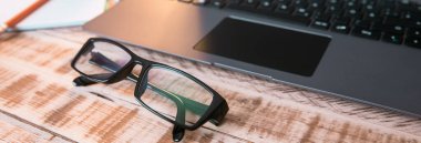 Masada dizüstü bilgisayarı ve not defteri olan gözlükler.